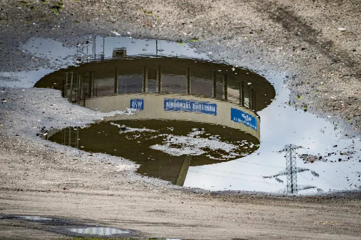 Round building reflected in a patch of melting snow